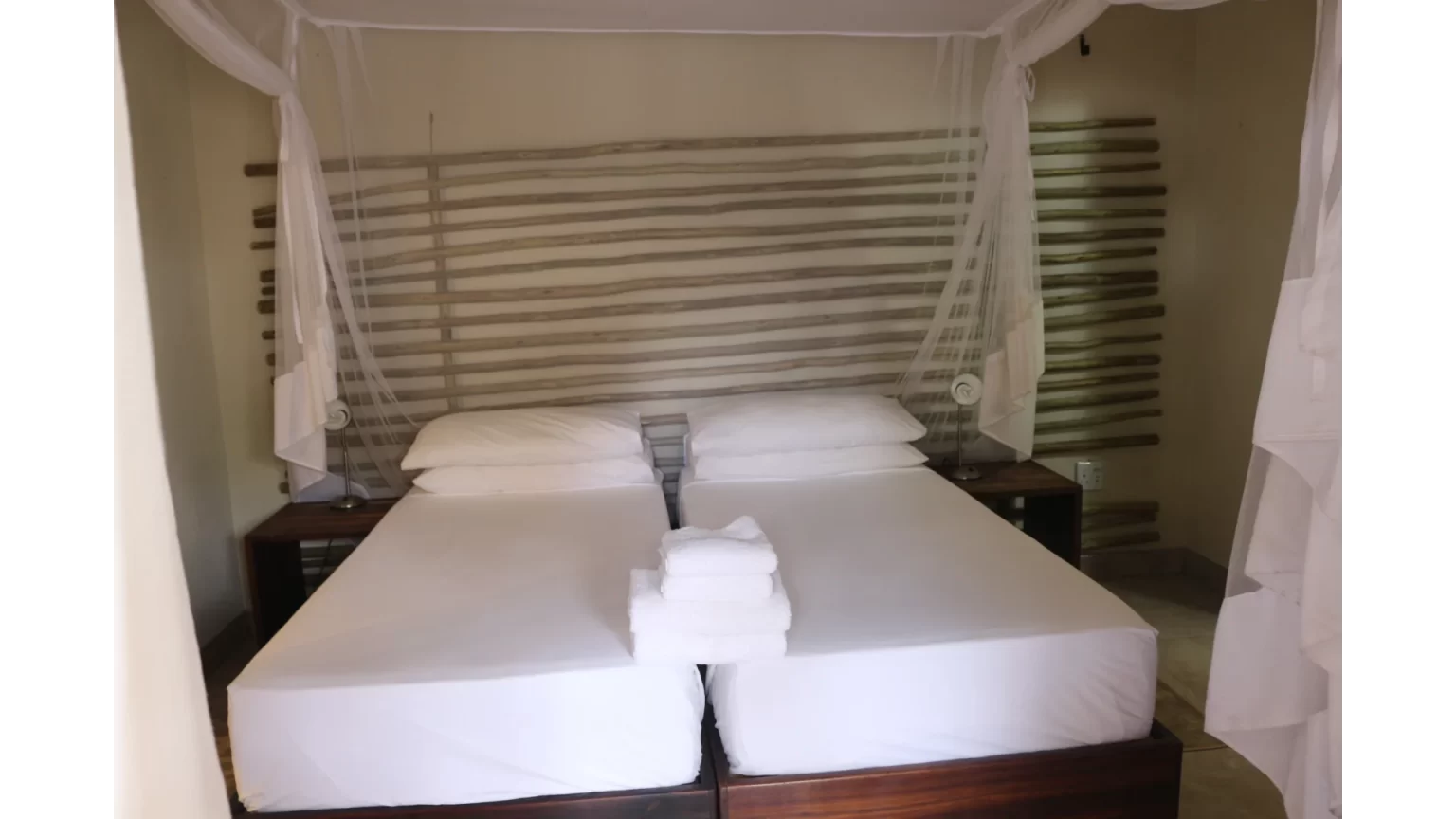 Twin beds under mosquito nets in a room at Okaukuejo Camp
