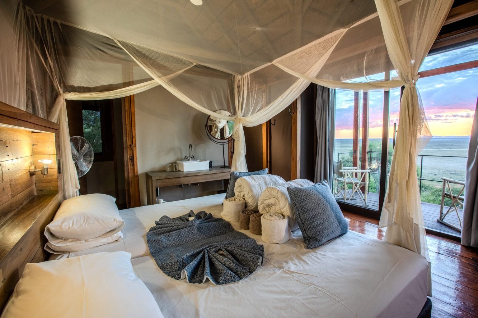 Chalet bedroom with four-poster bed and mosquito net at Dolomite Camp