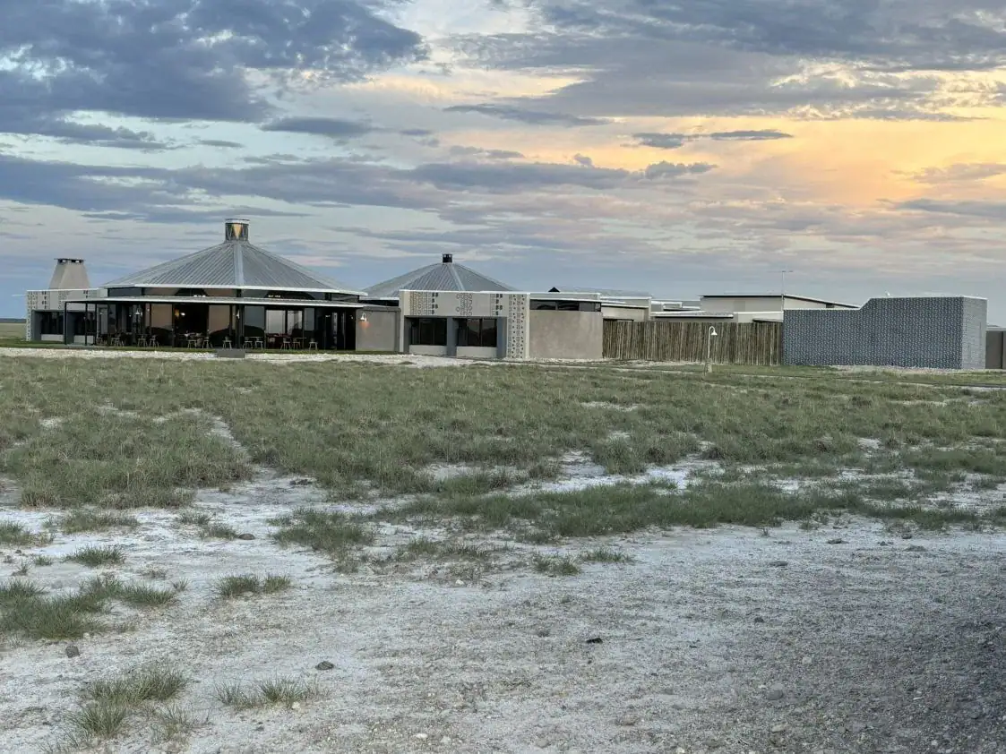 Etosha King Nehale Rates 2026 & Booking — Lodge at King Nehale Gate, Northern Etosha 6 Etosha King Nehale main lodge with Oshiwambo-inspired peaked roofs on the grassland north of Etosha