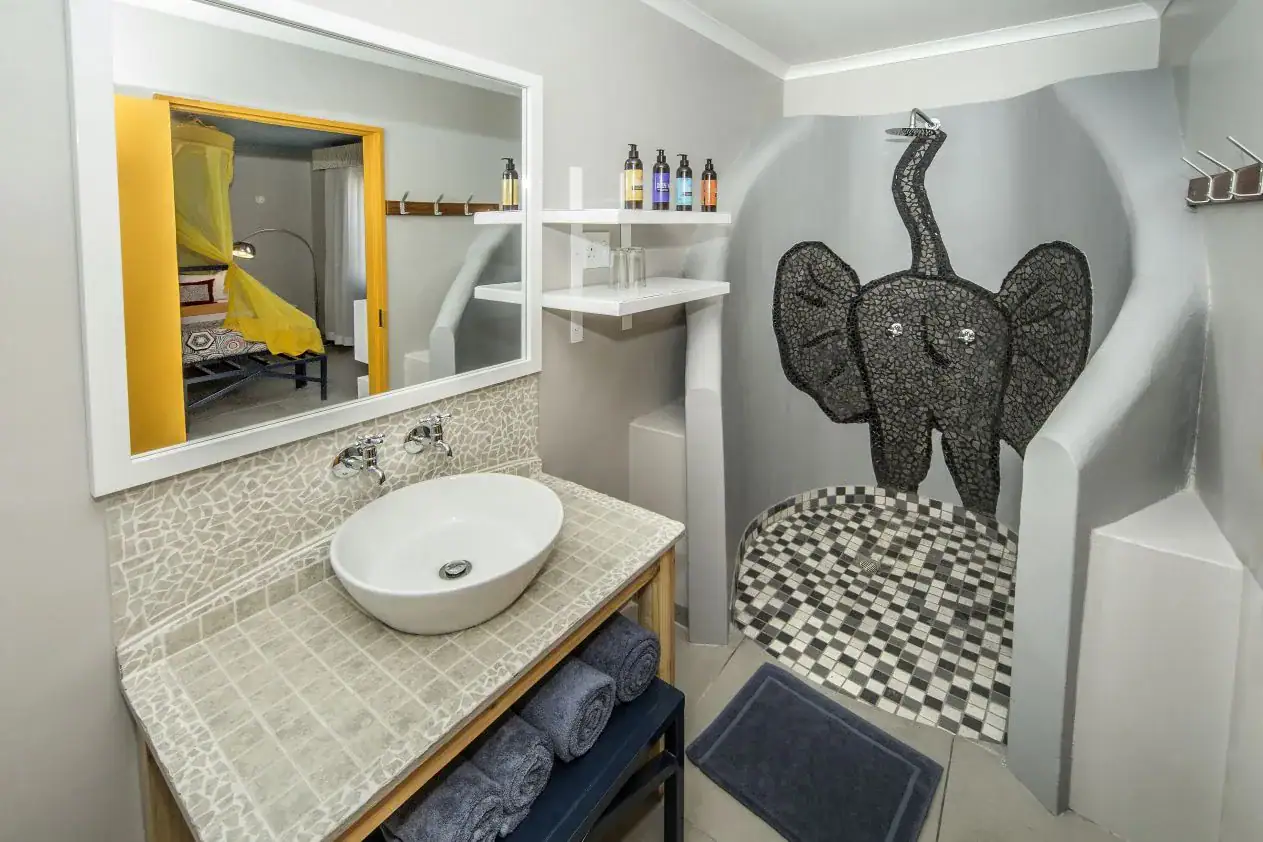 En-suite bathroom with sculpted walk-in shower decorated in an elephant mosaic at Etosha Safari Camp
