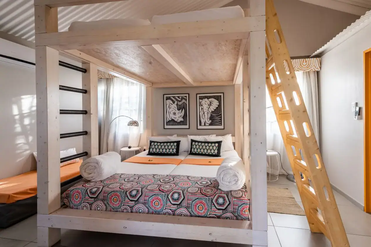 Family room with timber four-poster and loft bed with African-print bedspread at Etosha Safari Camp