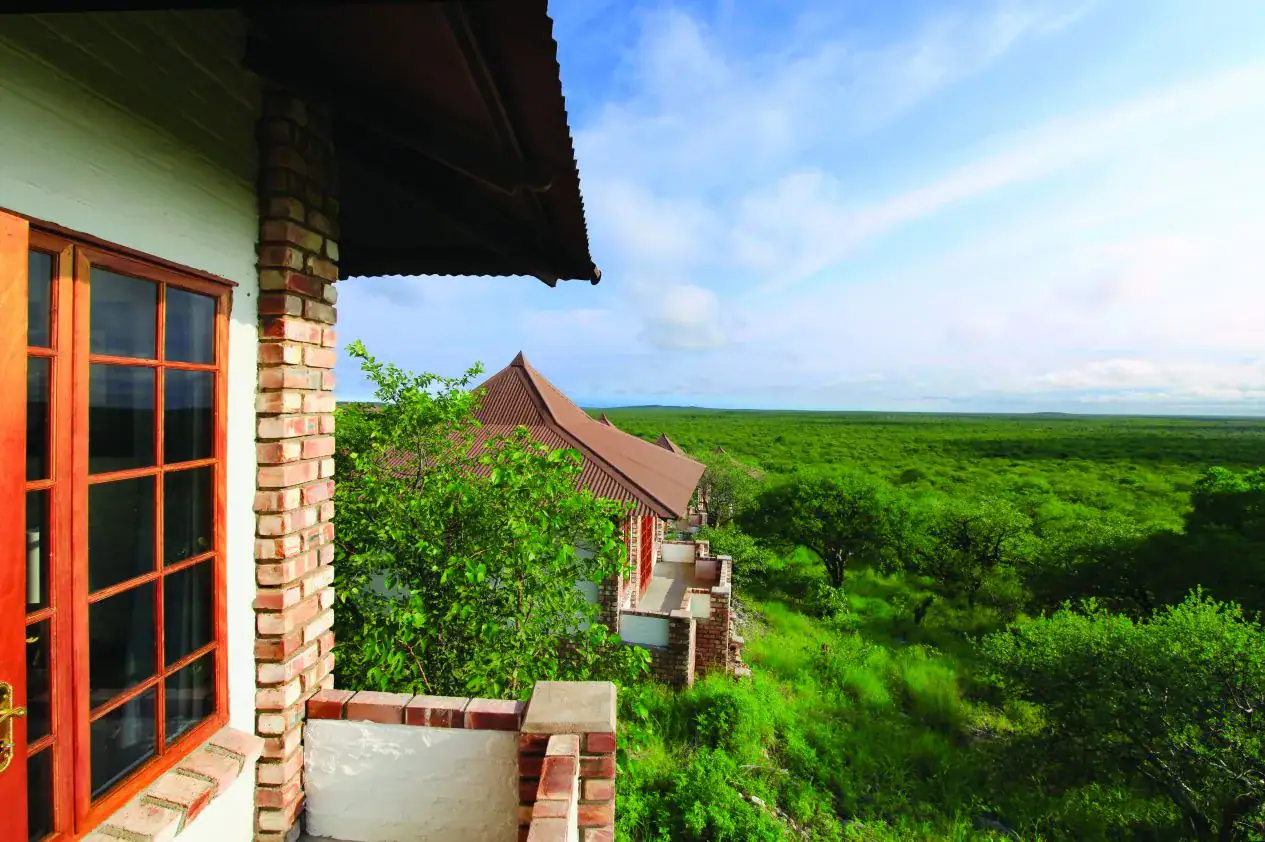 View from a bungalow balcony over green mopane woodland at Etosha Safari Lodge