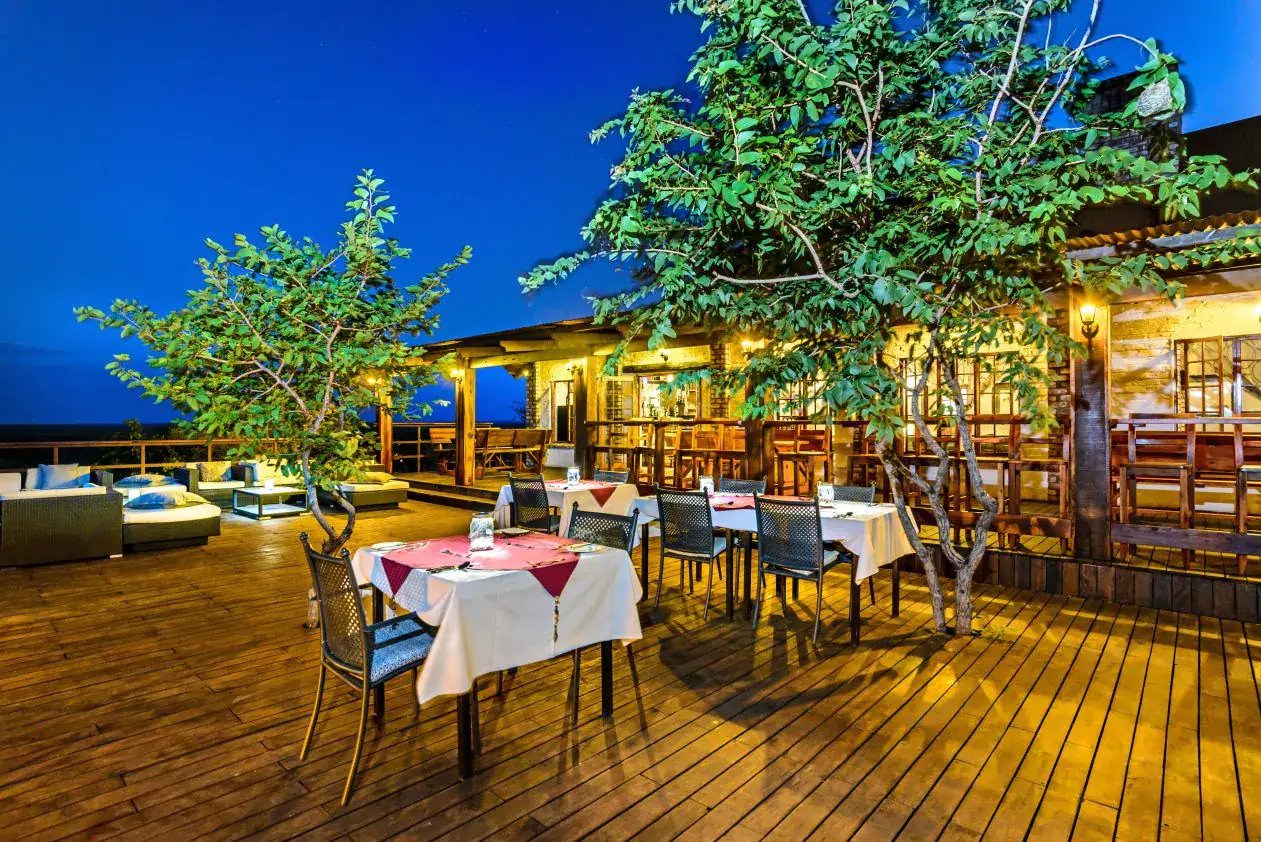 Candle-lit dinner tables on the wooden terrace deck at dusk at Etosha Safari Lodge