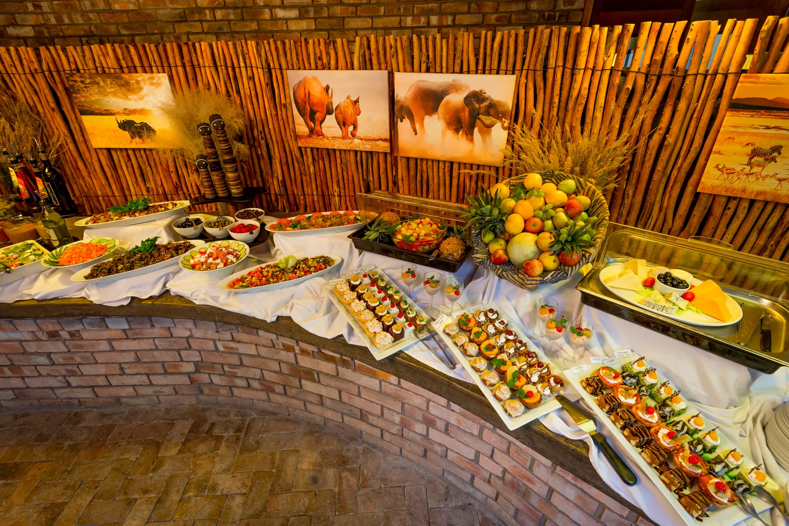 Buffet spread of salads, fresh fruit and desserts beneath African wildlife artwork at the Etosha Village restaurant