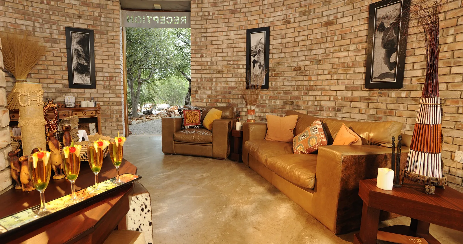 Reception lounge with leather sofas, wildlife prints and brick walls at Etosha Village