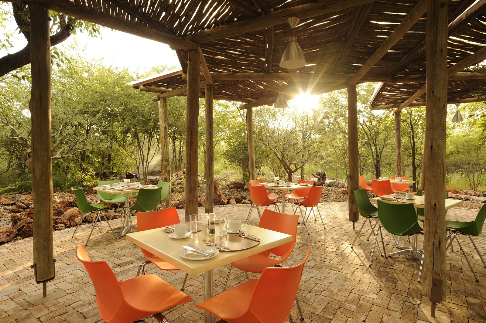 Open-sided restaurant terrace with a timber-pole roof and bush views at Etosha Village