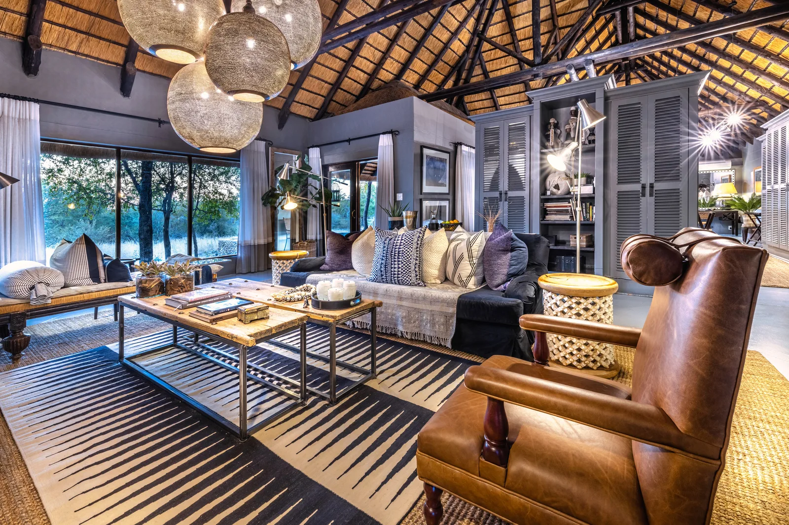 Villa Mushara lounge with leather wingback chair, filigree pendants and floor-to-ceiling bush views